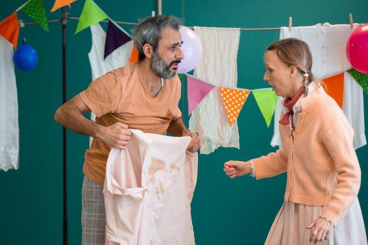 Yasso und die Nachbarin sprechen über den Kaffeefleck auf Yassos Hemd.