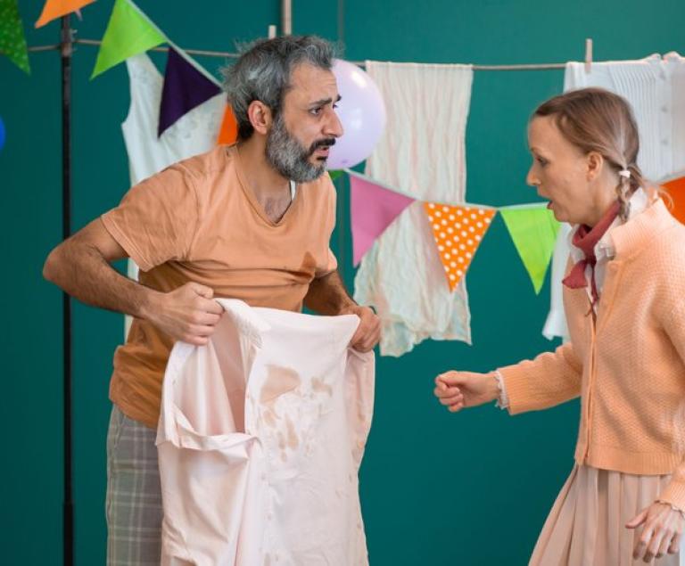 Yasso und die Nachbarin sprechen über den Kaffeefleck auf Yassos Hemd.