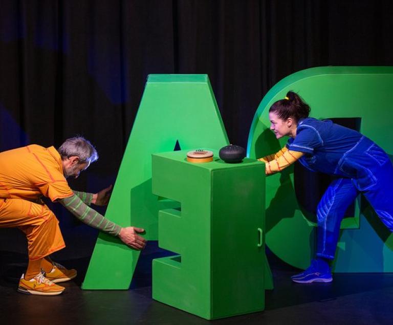 Zwei Kinder spielen mit großen Bauklötzen in Form von Buchstaben.