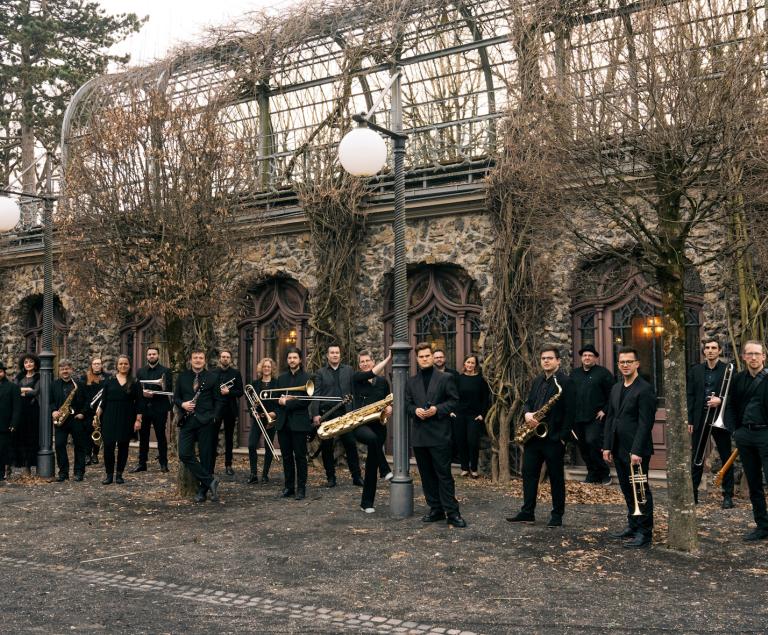 Eine Bigband steht mit ihren Instrumenten vor einer historischen Mauer