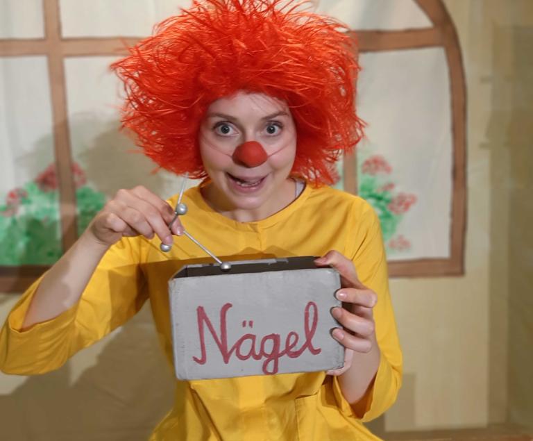 Ein Kobold mit roten Haaren hält eine Schachtel Nägel in der Hand.